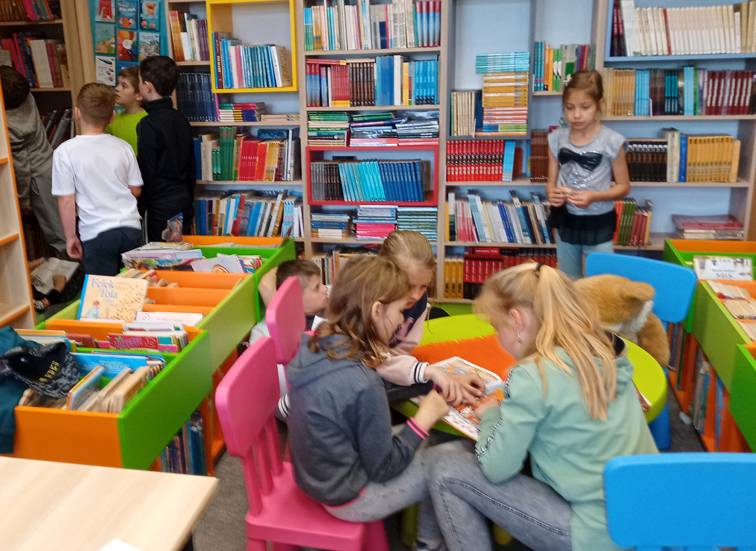 Uczniowie klasy drugiej Szkoły Podstawowej w Brzezinach podczas wyszukiwania książek do wypożyczenia.